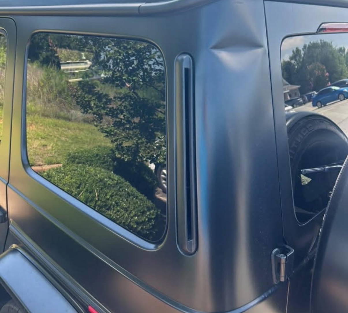 Sharp crease in the rear quarter panel of a matte black Mercedes G-Class before paintless dent repair